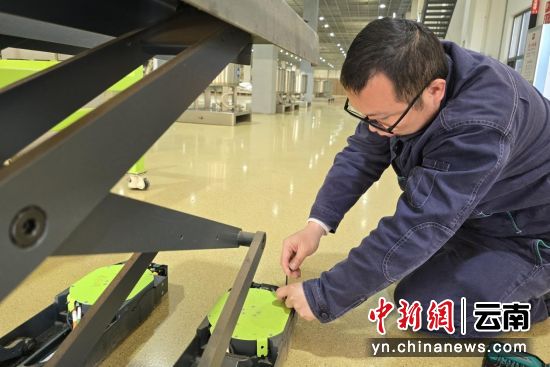 图为赵培成在检查AGV小车驱动轮状态。沈婧怡 摄 图为赵培成在检查AGV小车驱动轮状态。沈婧怡 摄