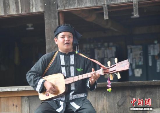 倪肯弹着布朗族牛腿琴演唱《结下情谊万年长》。 黄兴鸿 摄 倪肯弹着布朗族牛腿琴演唱《结下情谊万年长》。 黄兴鸿 摄